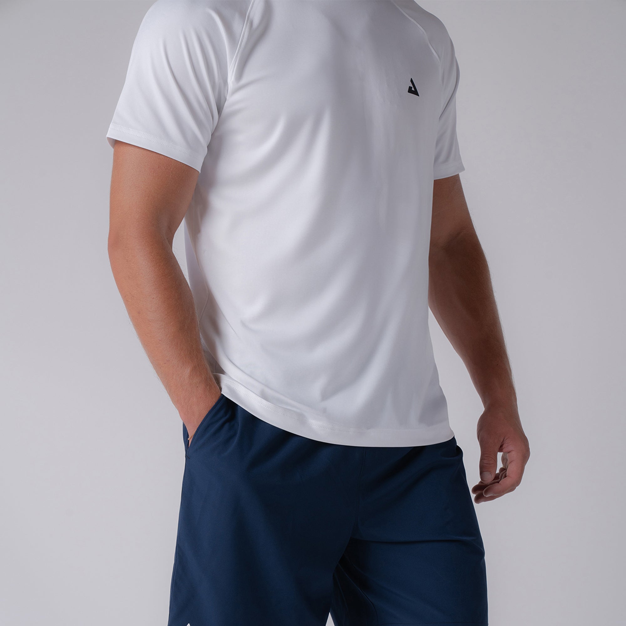 Close up image of a male model who is wearing a JOOLA men's court short sleeve shirt, white with black JOOLA trinity logo over the left chest.