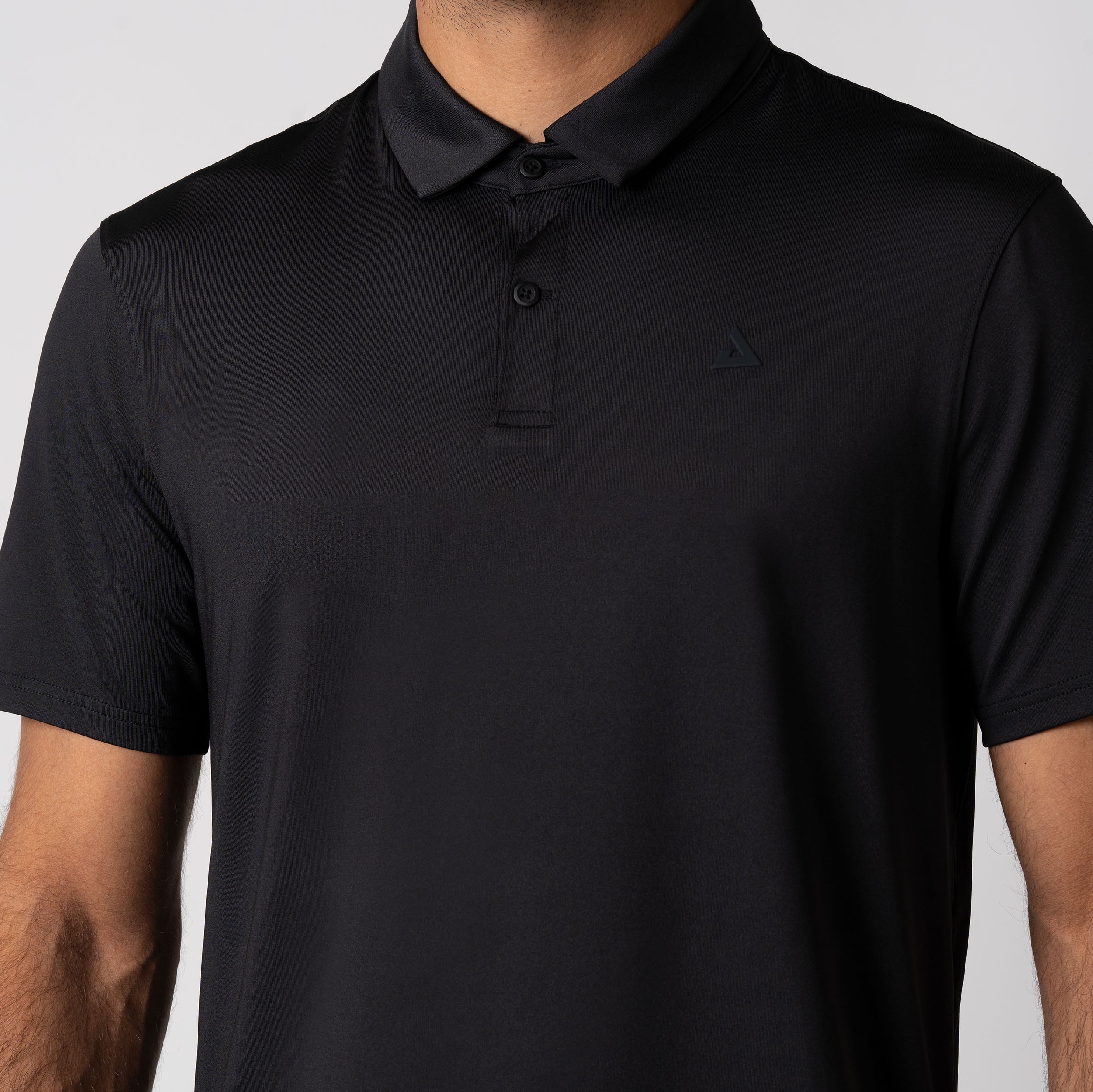 Close up image showing the buttons and color of a JOOLA men's club polo, black.