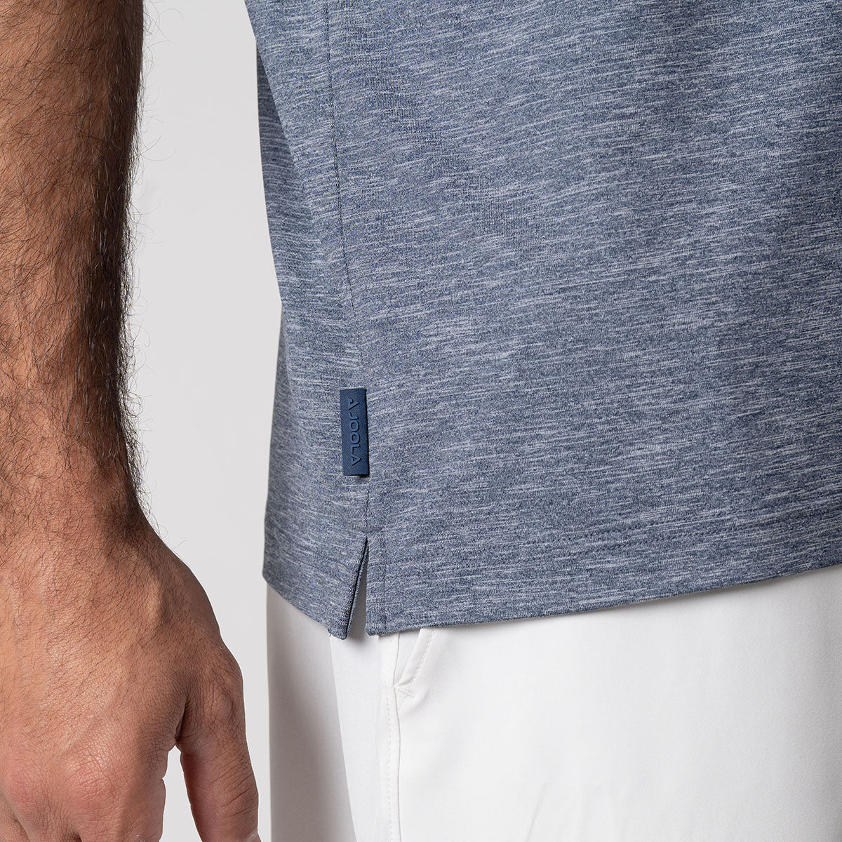Close up image of the raised JOOLA logo tag on a JOOLA men's club polo, navy heather.