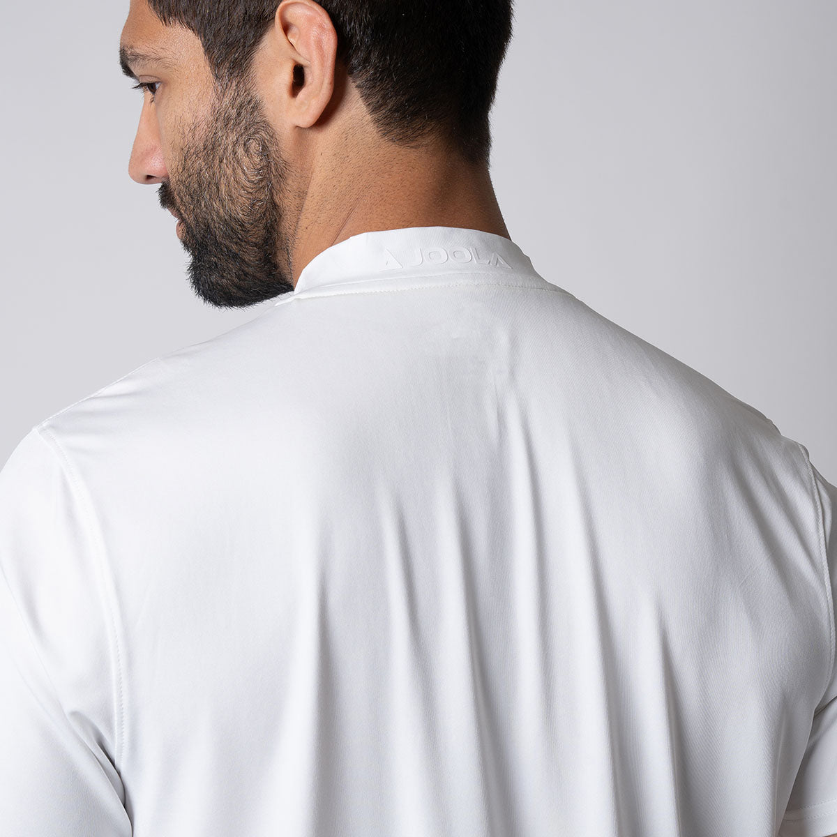 Image showing the back of a male model who is wearing a JOOLA men's court polo, white.