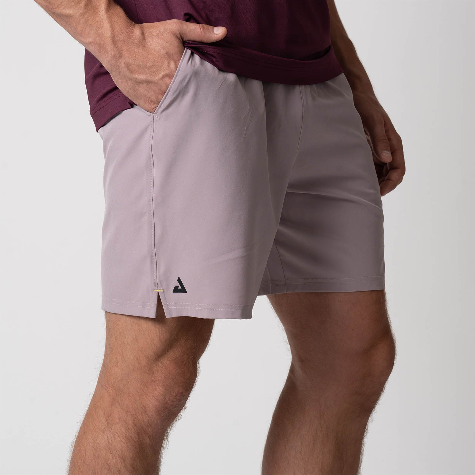 Close up image showing the JOOLA Trinity logo on the leg of a pair of JOOLA Men's Woven Shorts, 7 inch inseam, dusty mauve.