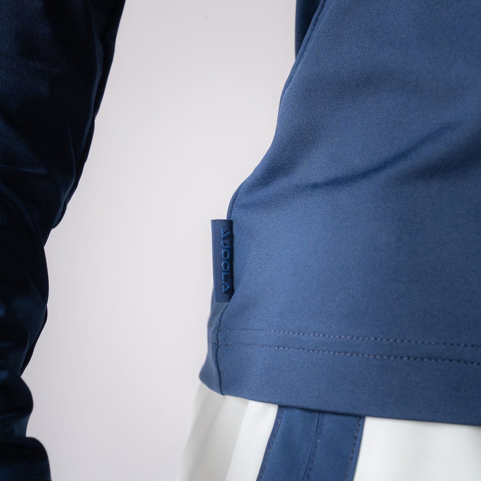 Close up image showing the detailed JOOLA Logo on the side of a Women's Quarter Zip Pullover, Navy.