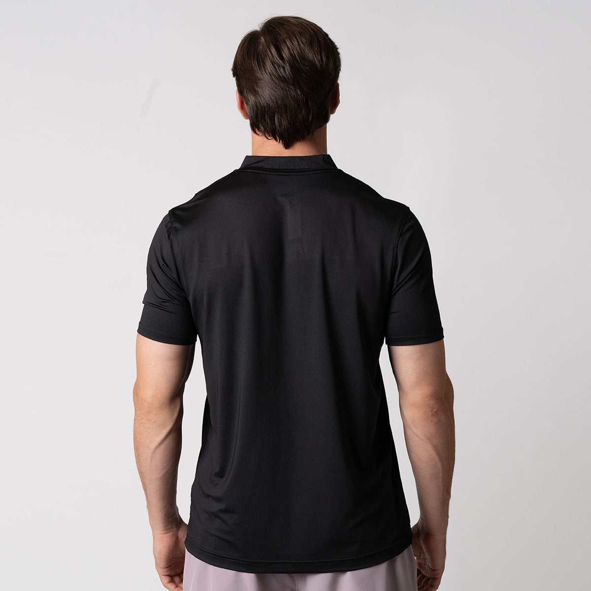 Image showing the back of a male model who is wearing a JOOLA men's court polo, black.