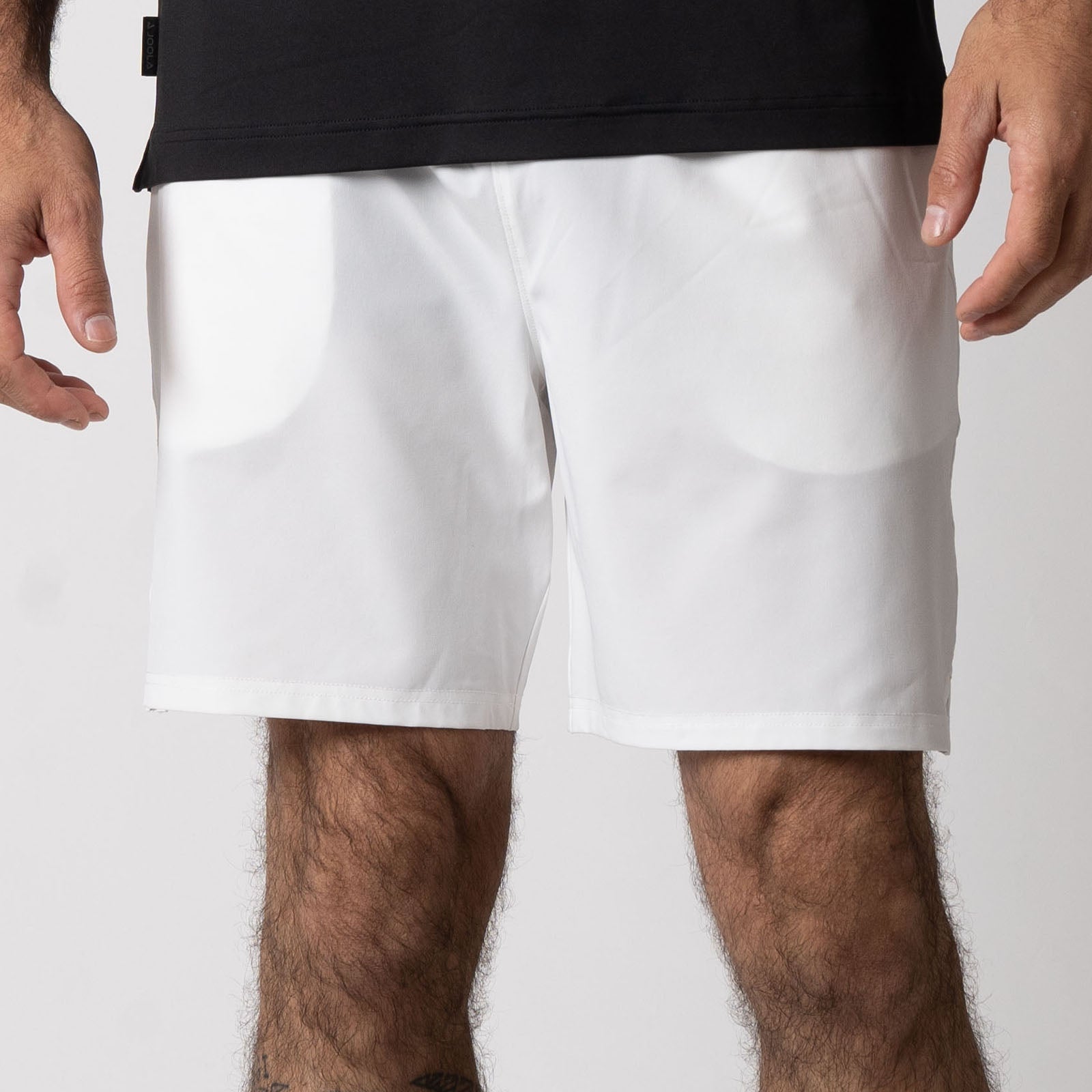 Close up image of a male model wearing a pair of JOOLA men's woven shorts, seven inch inseam, white.