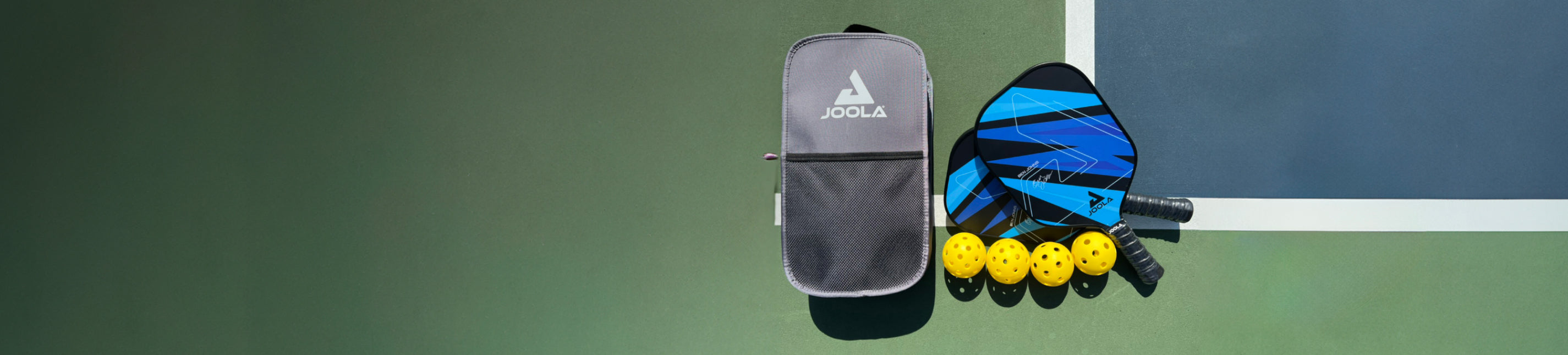 Horizontal banner image of a JOOLA Pickleball Paddle set laid out on a pickleball court.